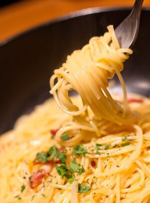 フォークの先にくるくる巻かれたクリーミーなカルボナーラ